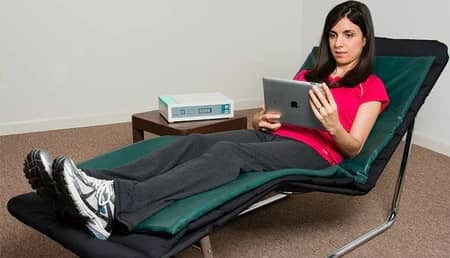 Woman seated on lounge chair using Curatron 3D PEMF coil system