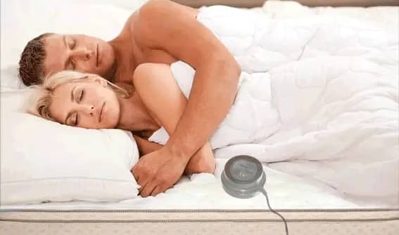 Couple resting in bed with EarthPulse V5 device positioned beside mattress