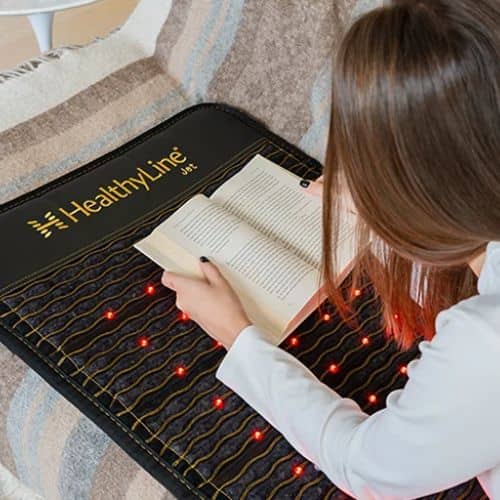 Woman lying on HealthyLine Jet Series PEMF mat while reading