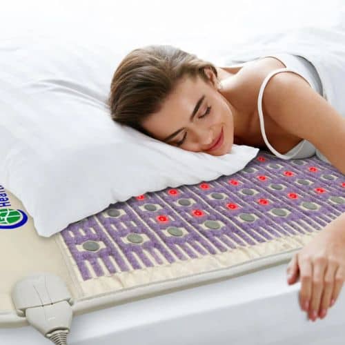 Woman resting on HealthyLine TAJ PEMF mat with pillow