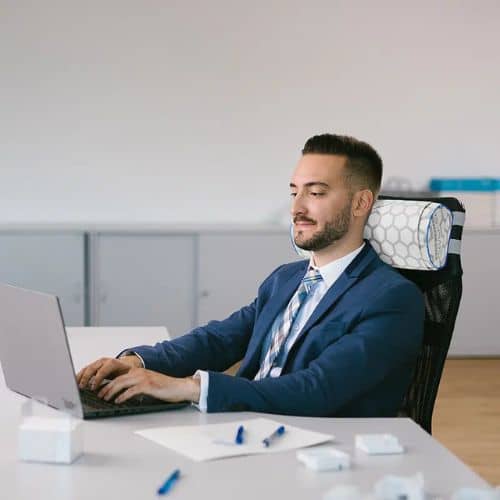 Man using Omnipemf neck cushion while working at desk