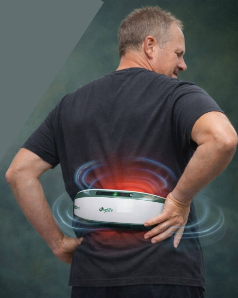 Man wearing a PEMF therapy belt on his lower back with blue pulsed electromagnetic waves and red pain indicators showing chronic lower back pain relief