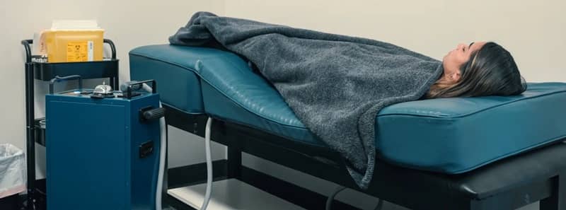 Woman lying on Pulse Centers PEMF massage bed with blanket during session